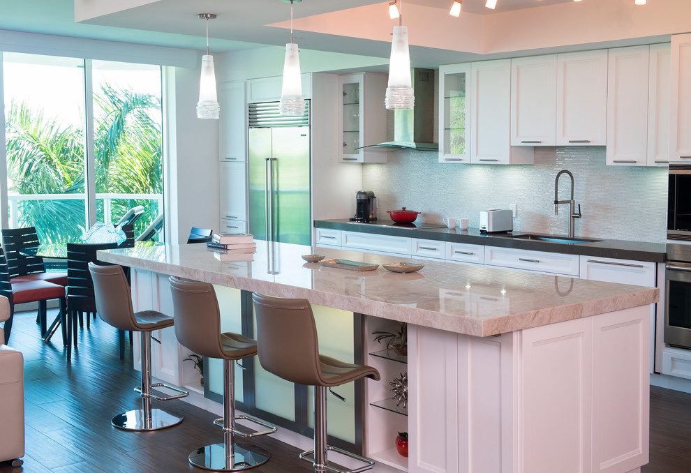 Inspiration for a large contemporary galley porcelain tile open concept kitchen remodel in Miami with an undermount sink, recessed-panel cabinets, white cabinets, quartzite countertops, white backsplash, glass tile backsplash, stainless steel appliances and an island