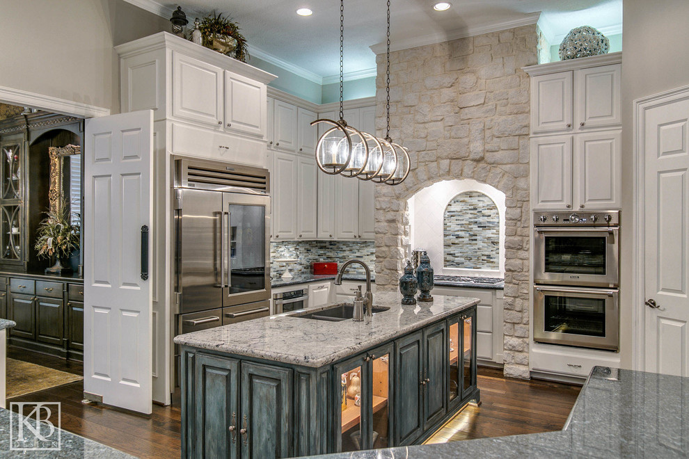 Photo of a rustic u-shaped enclosed kitchen in Houston with white cabinets, granite worktops, multi-coloured splashback, glass tiled splashback, stainless steel appliances, medium hardwood flooring and an island.