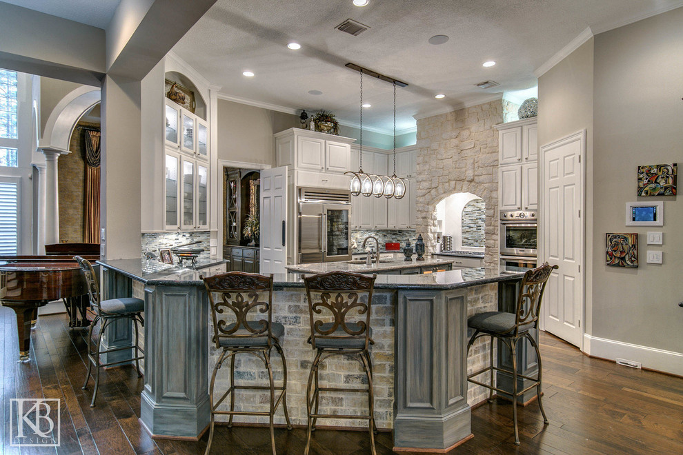 Modelo de cocinas en U rústico, cerrado, con puertas de armario blancas, encimera de granito, salpicadero multicolor, salpicadero de azulejos de vidrio, electrodomésticos de acero inoxidable, suelo de madera en tonos medios y una isla