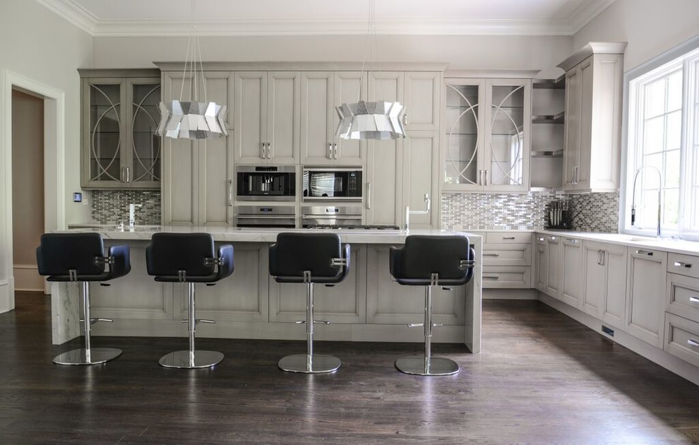 Moderne Wohnküche in L-Form mit Kücheninsel, Waschbecken, Schrankfronten mit vertiefter Füllung, weißen Schränken, Küchenrückwand in Grau, Küchengeräten aus Edelstahl und dunklem Holzboden in Atlanta