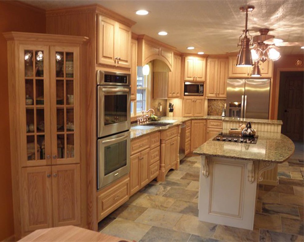 Foto på ett vintage kök, med en undermonterad diskho, luckor med upphöjd panel, skåp i ljust trä, granitbänkskiva, stänkskydd i keramik, rostfria vitvaror, travertin golv och en köksö