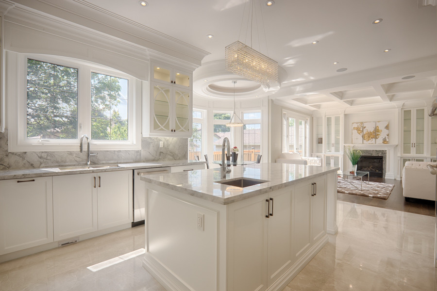 Modern inredning av ett stort grå grått kök, med en undermonterad diskho, skåp i shakerstil, vita skåp, marmorbänkskiva, grått stänkskydd, stänkskydd i marmor, rostfria vitvaror, klinkergolv i porslin, en köksö och beiget golv