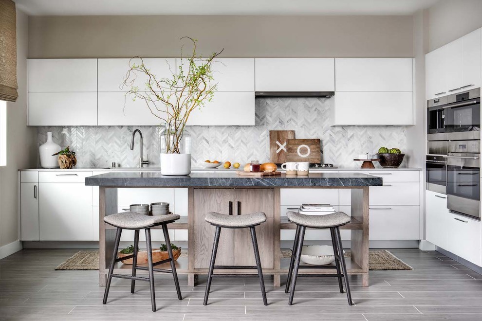 Inspiration for a mid-sized contemporary l-shaped gray floor and light wood floor enclosed kitchen remodel in Orange County with flat-panel cabinets, white cabinets, gray backsplash, marble backsplash, stainless steel appliances, an island, gray countertops and marble countertops
