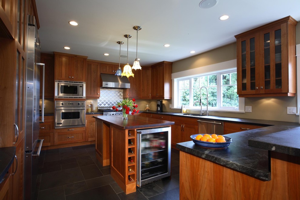Design ideas for a large traditional u-shaped kitchen/diner in Vancouver with a submerged sink, shaker cabinets, medium wood cabinets, quartz worktops, stainless steel appliances, ceramic flooring, an island, black floors and black worktops.