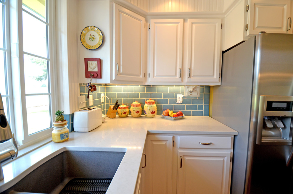 Exempel på ett klassiskt kök, med vita skåp, blått stänkskydd, rostfria vitvaror, mörkt trägolv, en köksö, en dubbel diskho, luckor med upphöjd panel, bänkskiva i kvarts och stänkskydd i keramik
