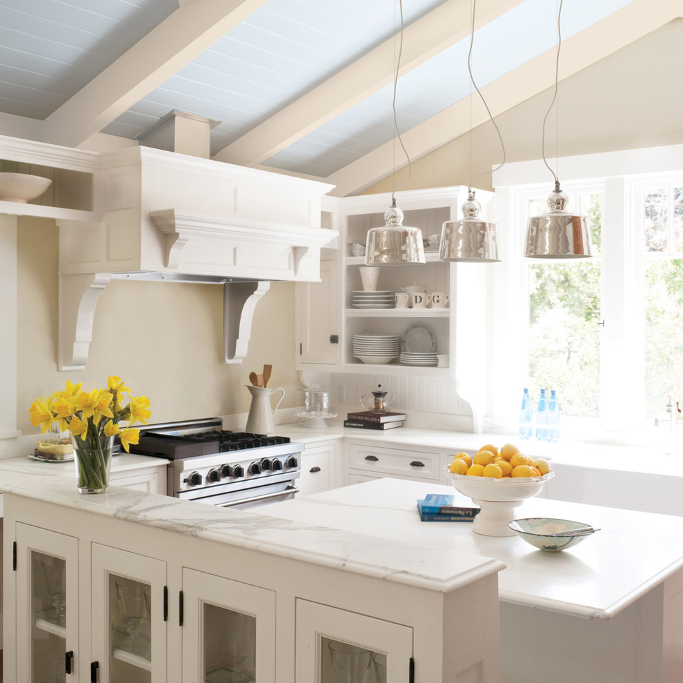 Inspiration for a mid-sized coastal galley open concept kitchen remodel in San Francisco with glass-front cabinets, white cabinets, marble countertops, beige backsplash, stainless steel appliances and a peninsula