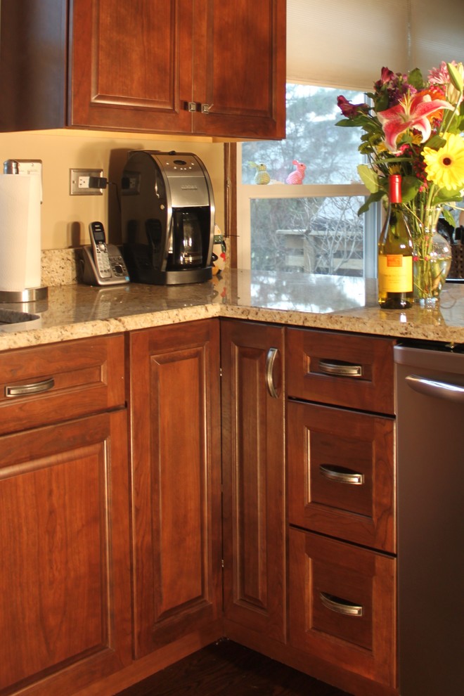 This is an example of a medium sized traditional u-shaped kitchen/diner in Chicago with a submerged sink, raised-panel cabinets, medium wood cabinets, granite worktops, stainless steel appliances, dark hardwood flooring and a breakfast bar.