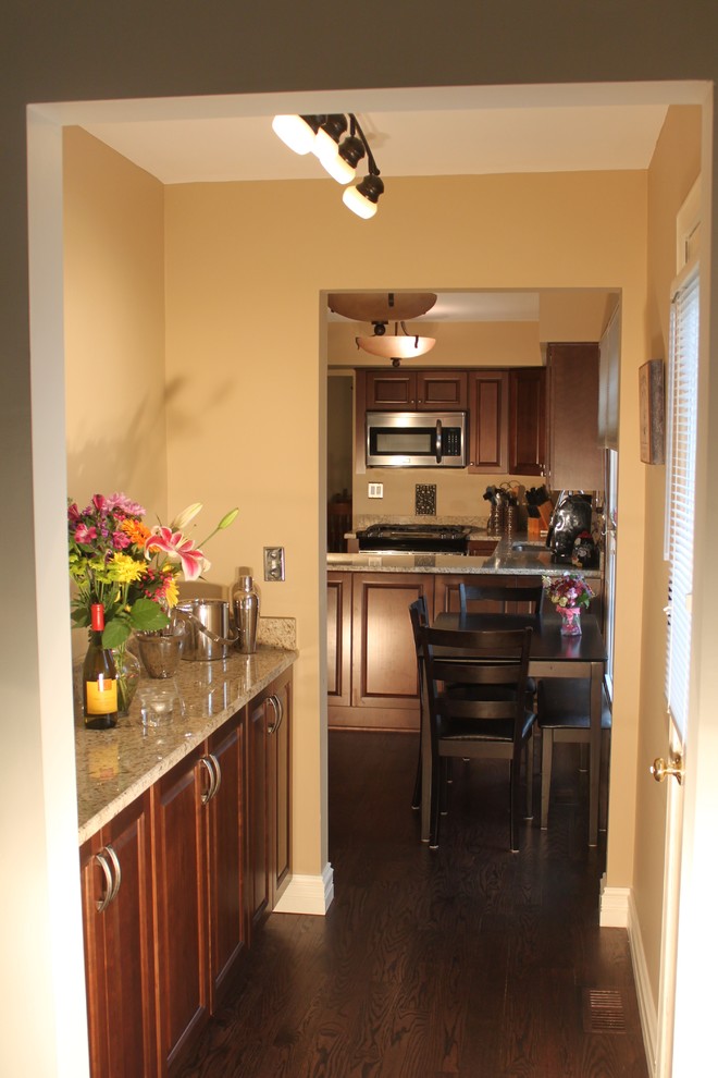 Bild på ett mellanstort vintage kök, med en undermonterad diskho, luckor med upphöjd panel, skåp i mellenmörkt trä, granitbänkskiva, rostfria vitvaror, mörkt trägolv och en halv köksö