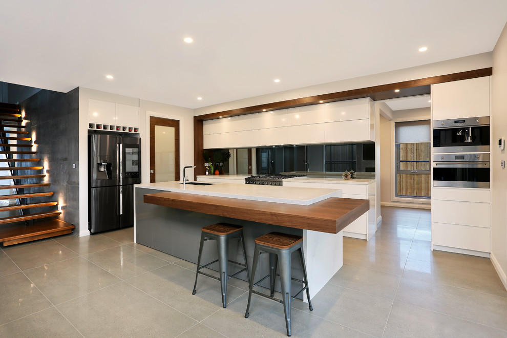 Idéer för ett stort modernt vit kök, med en undermonterad diskho, släta luckor, vita skåp, bänkskiva i kvarts, stänkskydd med metallisk yta, spegel som stänkskydd, rostfria vitvaror, klinkergolv i porslin, en köksö och grått golv