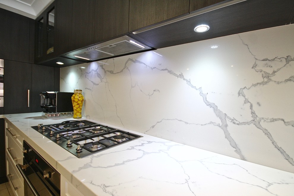 Design ideas for a medium sized contemporary u-shaped kitchen/diner in Sydney with a submerged sink, shaker cabinets, white cabinets, engineered stone countertops, white splashback, stone slab splashback, stainless steel appliances, ceramic flooring and no island.