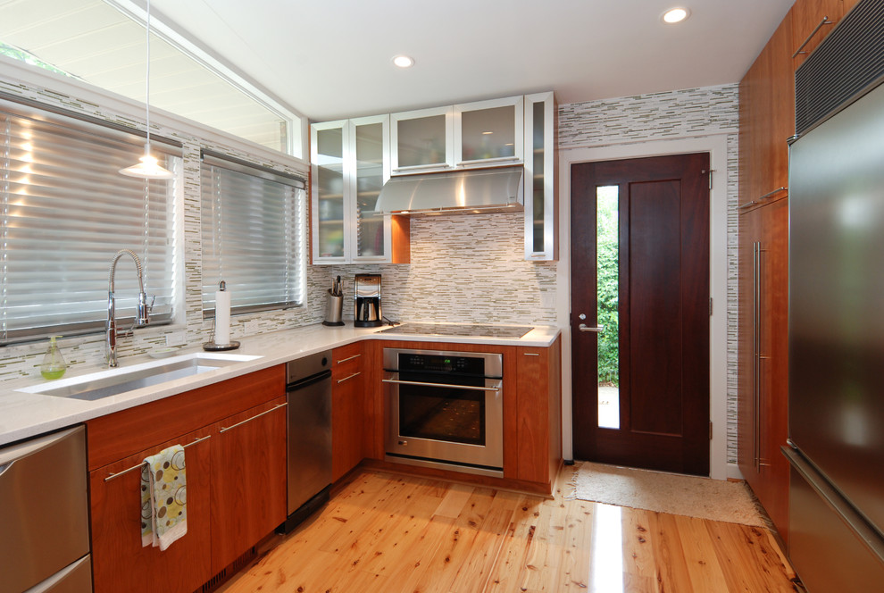 Foto på ett funkis u-kök, med rostfria vitvaror, släta luckor, skåp i mörkt trä, flerfärgad stänkskydd och stänkskydd i stickkakel