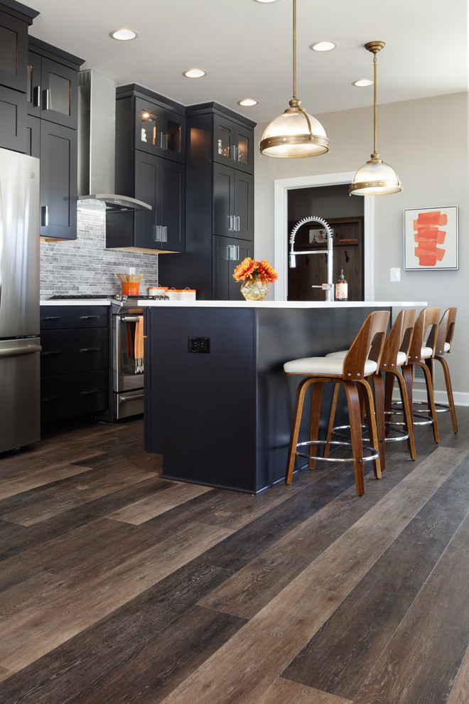 Eat-in kitchen - mid-sized transitional single-wall vinyl floor and brown floor eat-in kitchen idea in Other with an undermount sink, shaker cabinets, black cabinets, quartz countertops, gray backsplash, limestone backsplash, stainless steel appliances, an island and white countertops