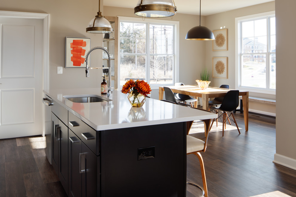 Bild på ett mellanstort vintage vit linjärt vitt kök och matrum, med en undermonterad diskho, skåp i shakerstil, svarta skåp, bänkskiva i kvarts, grått stänkskydd, stänkskydd i kalk, rostfria vitvaror, vinylgolv, en köksö och brunt golv
