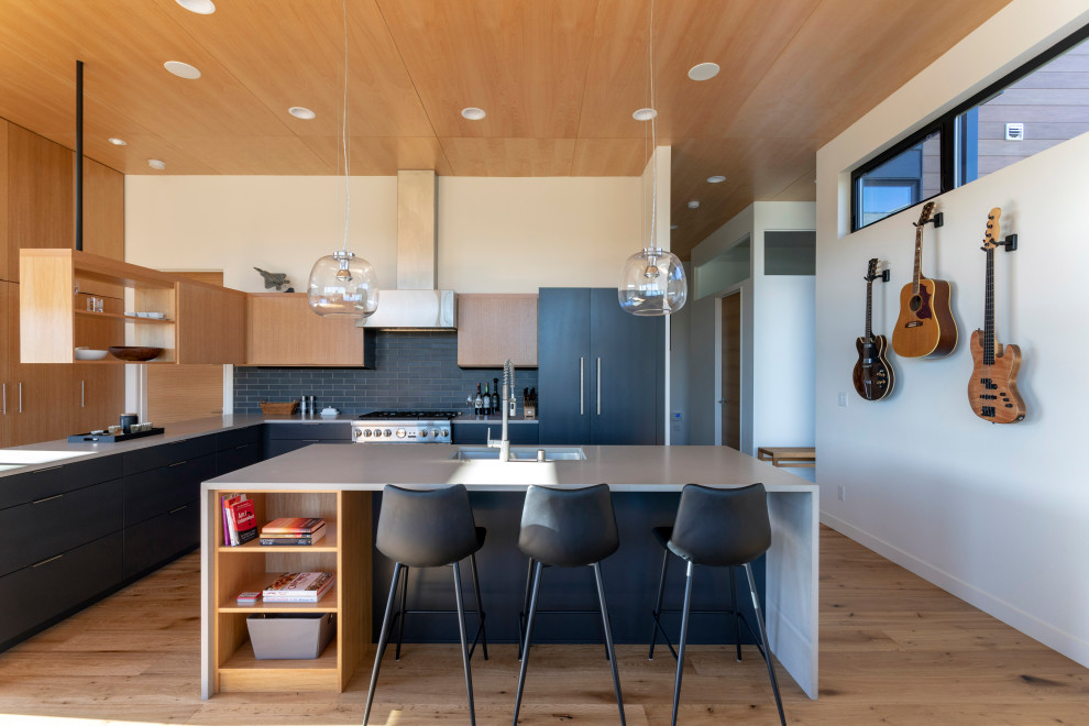 Inspiration for a contemporary l-shaped medium tone wood floor and brown floor kitchen remodel in Seattle with an undermount sink, flat-panel cabinets, black cabinets, paneled appliances, an island and gray countertops