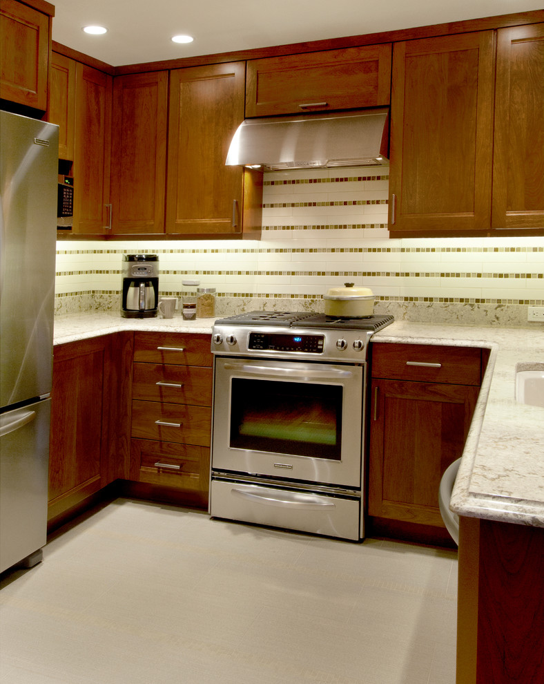 Exempel på ett avskilt, litet klassiskt u-kök, med en undermonterad diskho, luckor med infälld panel, skåp i mörkt trä, bänkskiva i kvarts, beige stänkskydd, stänkskydd i cementkakel, rostfria vitvaror och klinkergolv i porslin