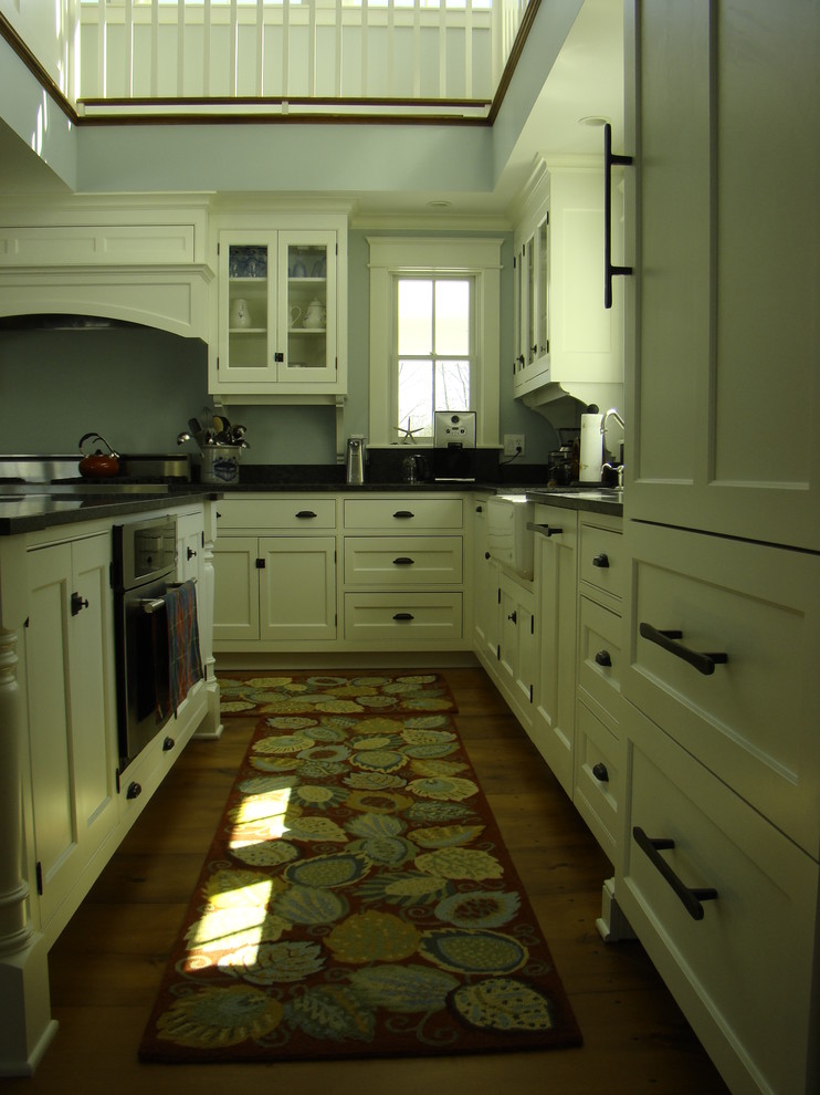 Example of a mid-sized classic l-shaped medium tone wood floor open concept kitchen design in Portland Maine with beaded inset cabinets, white cabinets, granite countertops, black backsplash, stone slab backsplash, paneled appliances and an island