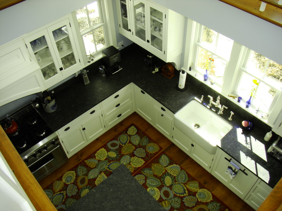 Пример оригинального дизайна: угловая кухня-гостиная среднего размера в классическом стиле с с полувстраиваемой мойкой (с передним бортиком), фасадами с декоративным кантом, белыми фасадами, гранитной столешницей, черным фартуком, фартуком из каменной плиты, техникой под мебельный фасад, паркетным полом среднего тона и островом