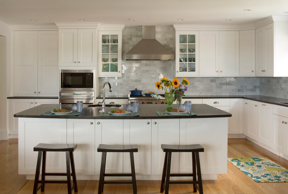 Open concept kitchen - mid-sized traditional l-shaped open concept kitchen idea in Boston with shaker cabinets, white cabinets, gray backsplash, stainless steel appliances, an island, an undermount sink, granite countertops and marble backsplash