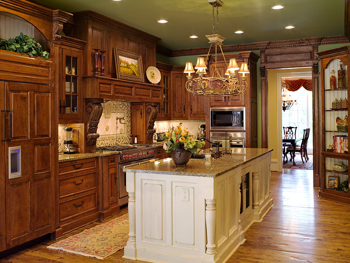 Example of a large classic u-shaped medium tone wood floor and brown floor eat-in kitchen design in Atlanta with an undermount sink, raised-panel cabinets, dark wood cabinets, granite countertops, multicolored backsplash, travertine backsplash, paneled appliances, an island and multicolored countertops