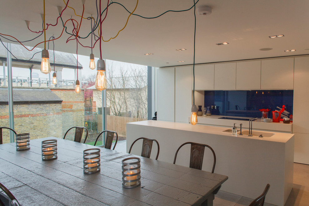 Zweizeilige Moderne Wohnküche mit flächenbündigen Schrankfronten, integriertem Waschbecken, Mineralwerkstoff-Arbeitsplatte, Küchenrückwand in Blau und Glasrückwand in London