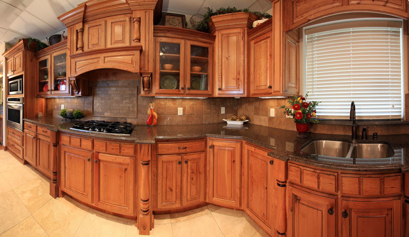 Klassisk inredning av ett stort l-kök, med en undermonterad diskho, luckor med upphöjd panel, skåp i slitet trä, granitbänkskiva, brunt stänkskydd, stänkskydd i stenkakel, rostfria vitvaror och klinkergolv i porslin