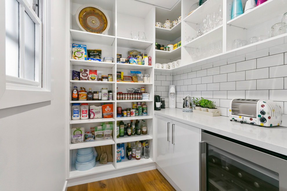 Moderne Küche in L-Form mit Vorratsschrank, Quarzwerkstein-Arbeitsplatte, Küchenrückwand in Weiß, Rückwand aus Metrofliesen, Küchengeräten aus Edelstahl und weißer Arbeitsplatte in Sydney