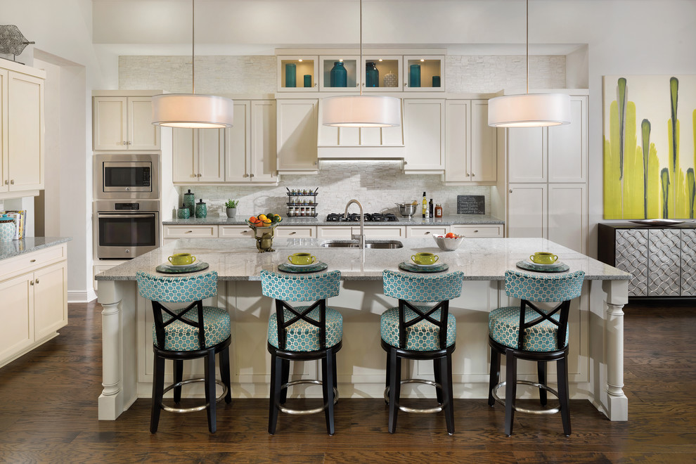 Inspiration for a large tropical l-shaped medium tone wood floor eat-in kitchen remodel in Tampa with an undermount sink, recessed-panel cabinets, white cabinets, granite countertops, gray backsplash, ceramic backsplash, stainless steel appliances and an island