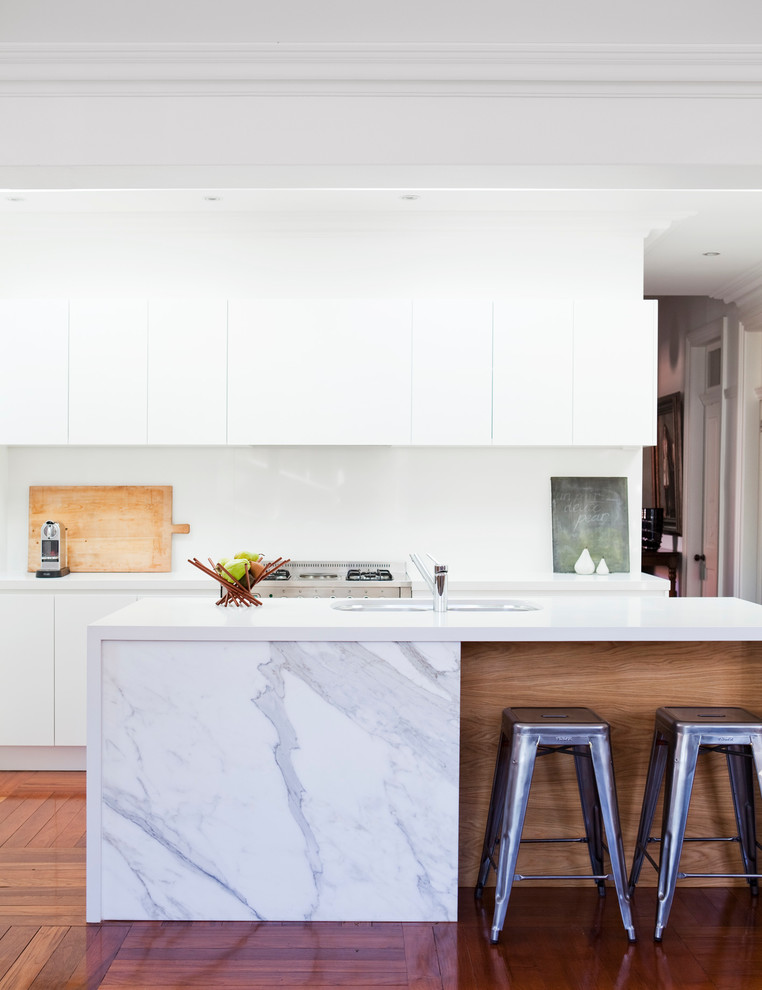Moderne Küche mit flächenbündigen Schrankfronten, weißen Schränken, Küchenrückwand in Weiß, dunklem Holzboden und Kücheninsel in Sydney