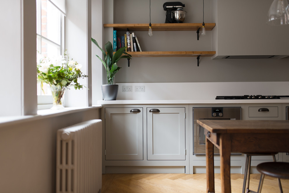 Aménagement d'une petite cuisine classique en bois clair fermée avec un placard à porte shaker et un sol en bois brun.