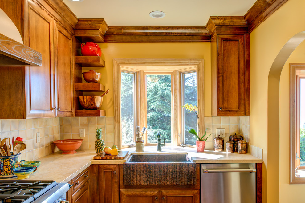 Inspiration för ett litet medelhavsstil l-kök, med en rustik diskho, luckor med infälld panel, skåp i mellenmörkt trä, beige stänkskydd och rostfria vitvaror