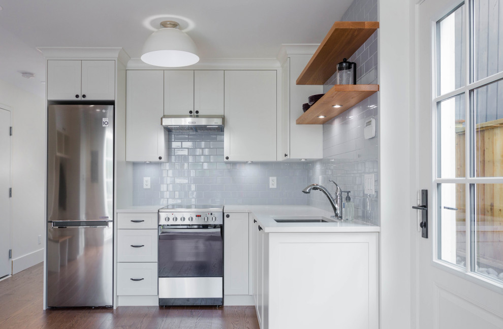 Inspiration for a small transitional l-shaped medium tone wood floor and brown floor eat-in kitchen remodel in Vancouver with an undermount sink, shaker cabinets, white cabinets, quartz countertops, subway tile backsplash, stainless steel appliances, no island and white countertops
