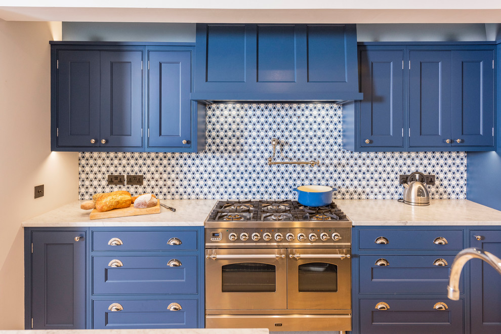 Exempel på ett stort industriellt vit vitt kök, med luckor med infälld panel, blå skåp, marmorbänkskiva, flerfärgad stänkskydd, rostfria vitvaror, ljust trägolv, en köksö, en rustik diskho och vitt golv