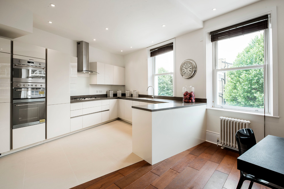 ロンドンにあるコンテンポラリースタイルのおしゃれなキッチン (フラットパネル扉のキャビネット、白いキャビネット、白いキッチンパネル、シルバーの調理設備) の写真