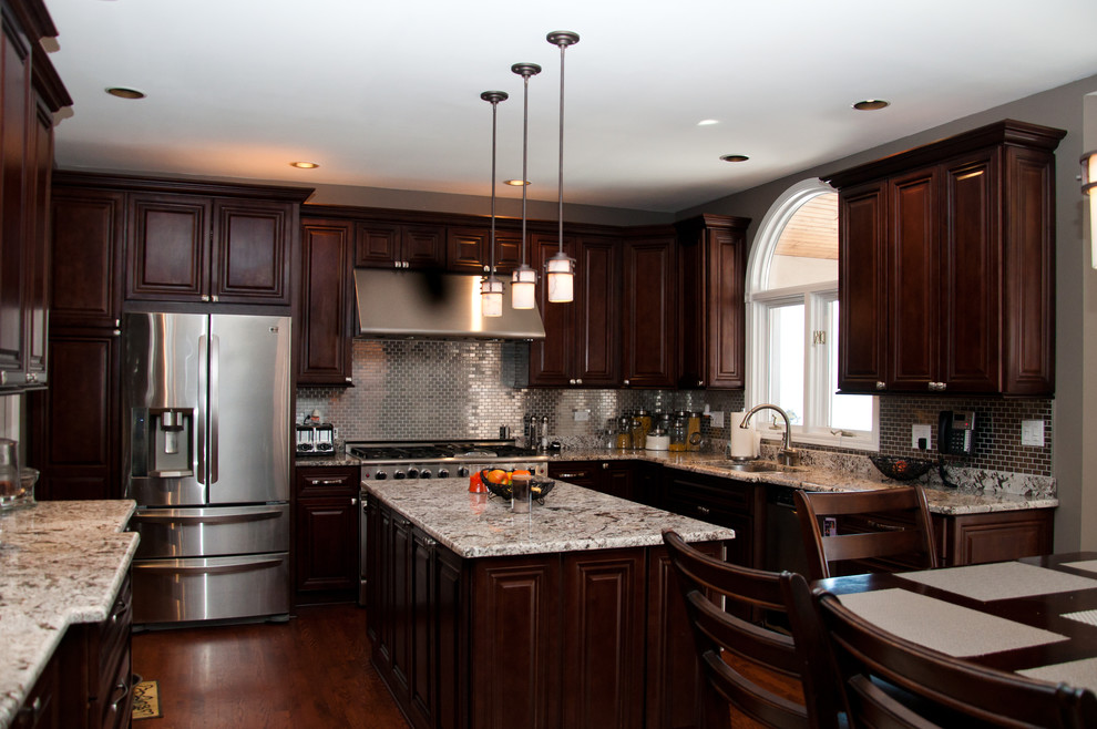 Eat-in kitchen - mid-sized transitional u-shaped medium tone wood floor eat-in kitchen idea in Cleveland with an undermount sink, raised-panel cabinets, dark wood cabinets, granite countertops, metallic backsplash, metal backsplash, stainless steel appliances and an island