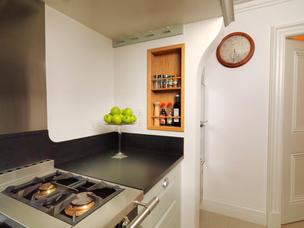 Modern inredning av ett mellanstort svart svart kök, med en integrerad diskho, luckor med upphöjd panel, gröna skåp, granitbänkskiva, rostfria vitvaror, kalkstensgolv, en köksö och vitt golv