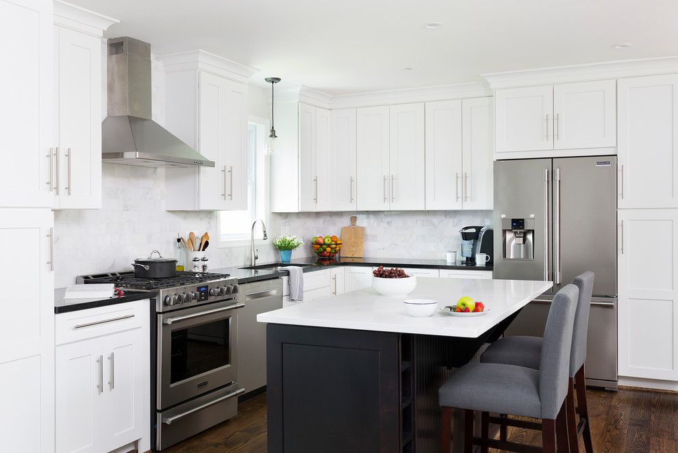 Photo of a large traditional l-shaped kitchen/diner in DC Metro with white cabinets, grey splashback, marble splashback, stainless steel appliances, medium hardwood flooring, an island and shaker cabinets.