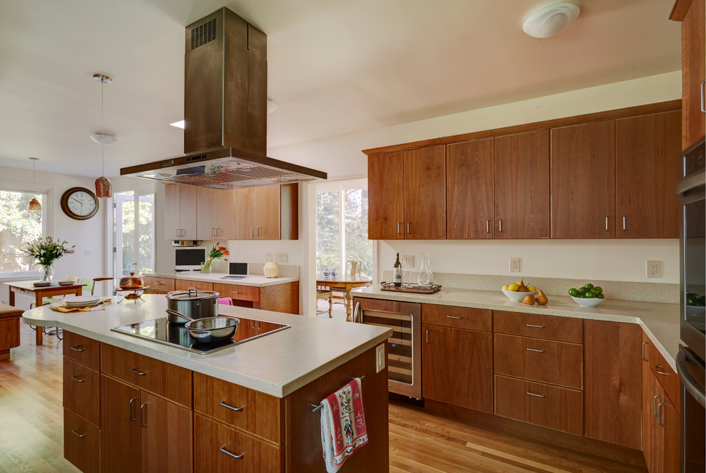 Design ideas for a large traditional u-shaped kitchen/diner in San Francisco with a submerged sink, flat-panel cabinets, medium wood cabinets, composite countertops, beige splashback, stone slab splashback, stainless steel appliances, light hardwood flooring and an island.