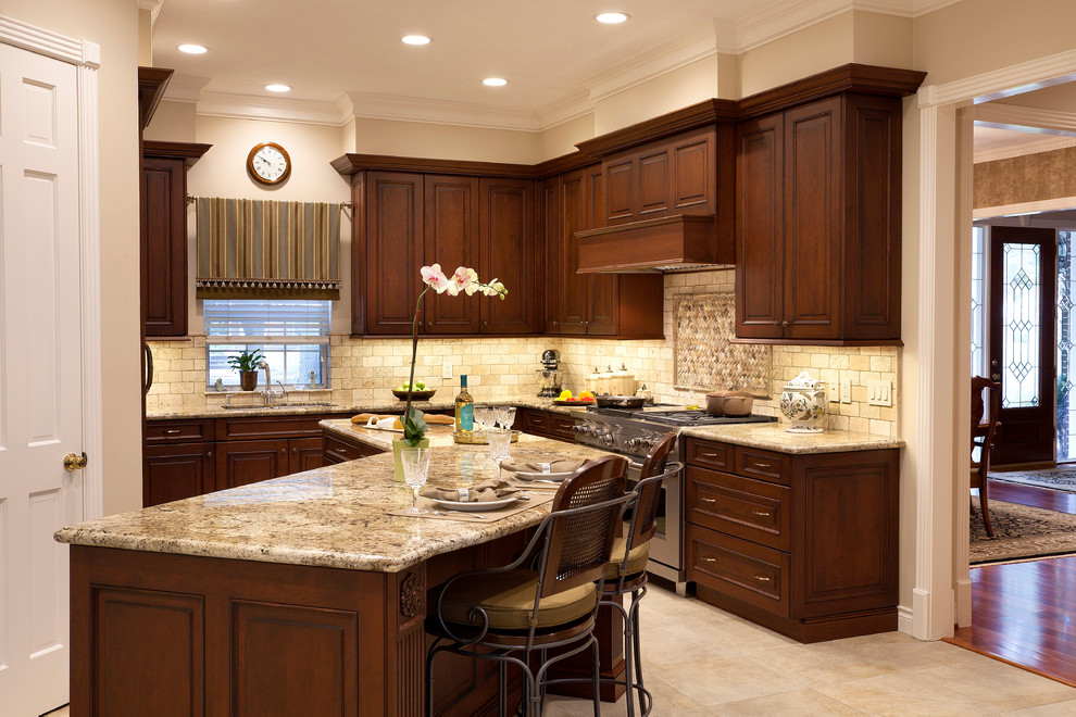 Mid-sized elegant l-shaped porcelain tile and beige floor eat-in kitchen photo in Houston with raised-panel cabinets, dark wood cabinets, granite countertops, beige backsplash, stainless steel appliances, an island, an undermount sink and cement tile backsplash