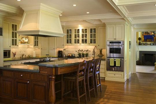 This is an example of a large classic l-shaped enclosed kitchen in San Francisco with beaded cabinets, beige cabinets, granite worktops, beige splashback, stainless steel appliances, bamboo flooring and an island.