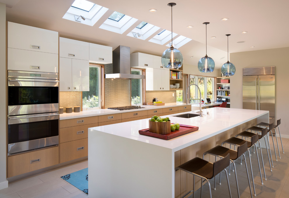 Contemporary galley kitchen in San Francisco with a submerged sink, flat-panel cabinets, composite countertops, grey splashback, ceramic splashback, stainless steel appliances, ceramic flooring, an island and white cabinets.