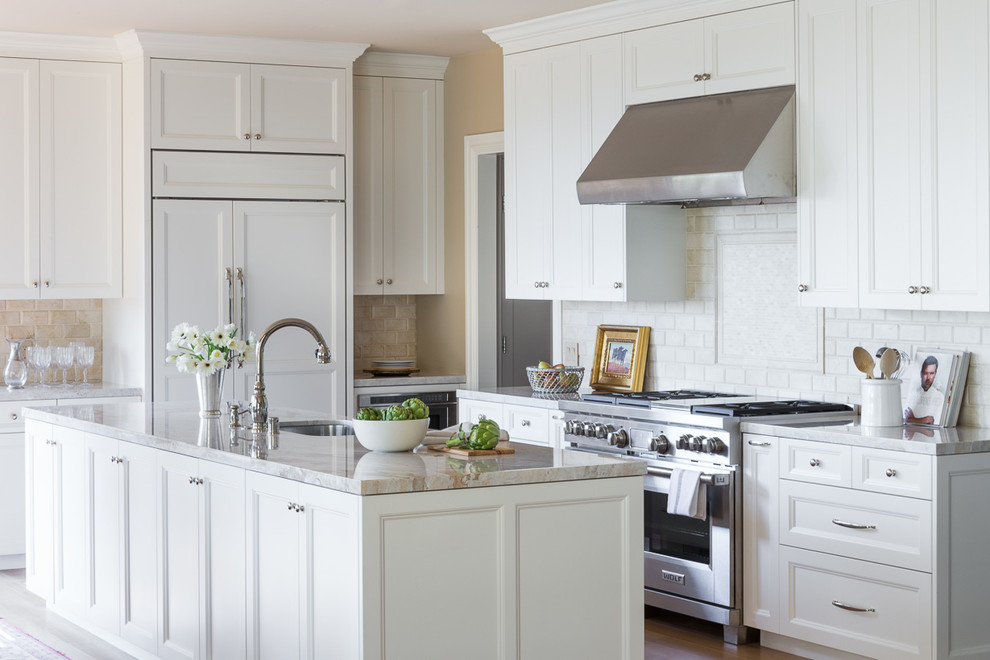 Elegant l-shaped kitchen photo in San Francisco with an undermount sink, recessed-panel cabinets, white cabinets, white backsplash, paneled appliances and an island