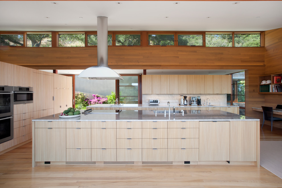 Inspiration for a contemporary u-shaped kitchen in San Francisco with an island, a submerged sink, flat-panel cabinets, light wood cabinets, stainless steel appliances and light hardwood flooring.
