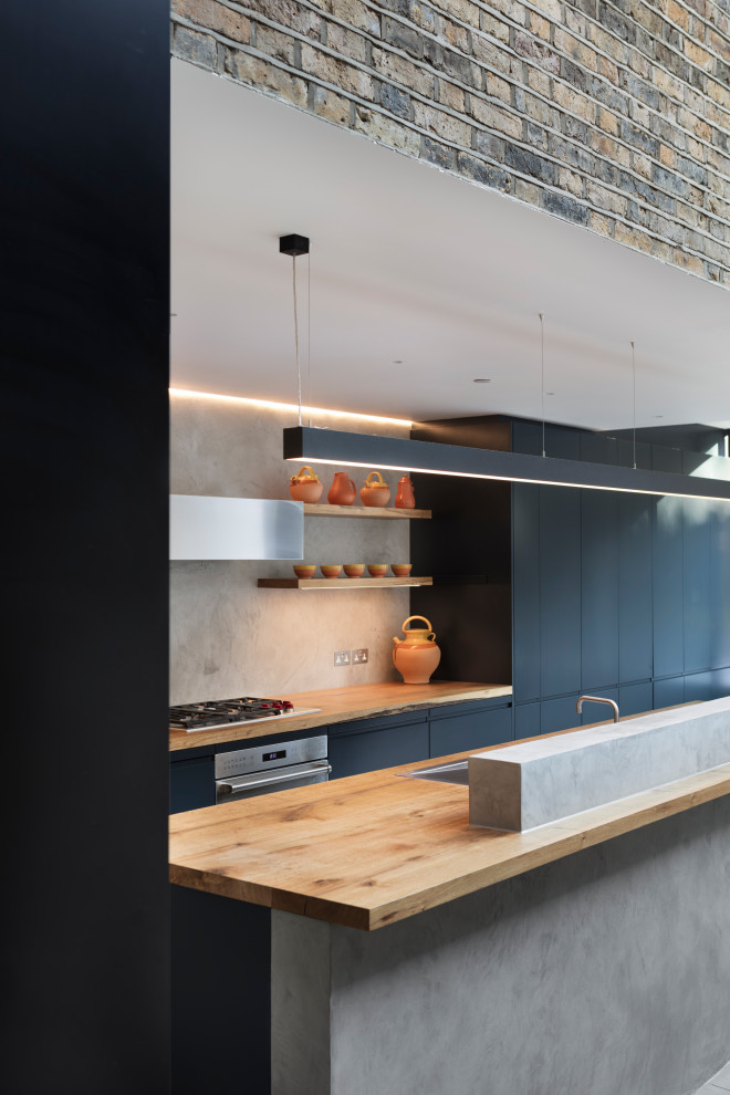 Inspiration för stora moderna brunt kök, med en nedsänkt diskho, släta luckor, blå skåp, träbänkskiva, grått stänkskydd, integrerade vitvaror, betonggolv, en köksö och grått golv