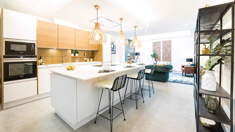 Стильный дизайн: большая прямая кухня-гостиная в современном стиле с врезной мойкой, плоскими фасадами, островом и серым полом - последний тренд