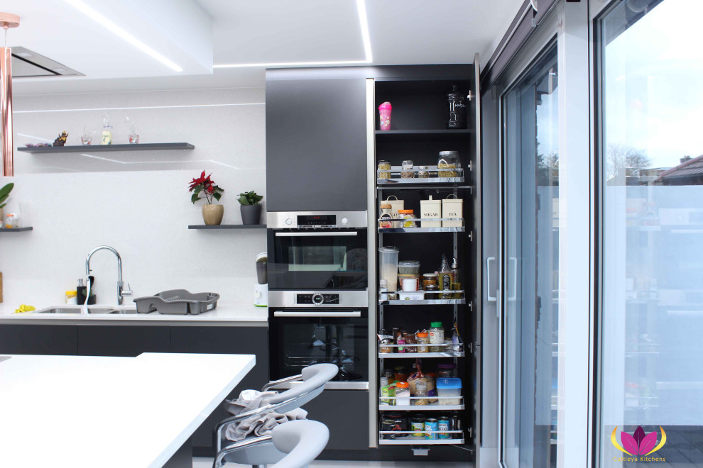 Foto på ett funkis vit kök, med en dubbel diskho, svarta skåp, vitt stänkskydd, rostfria vitvaror och en köksö