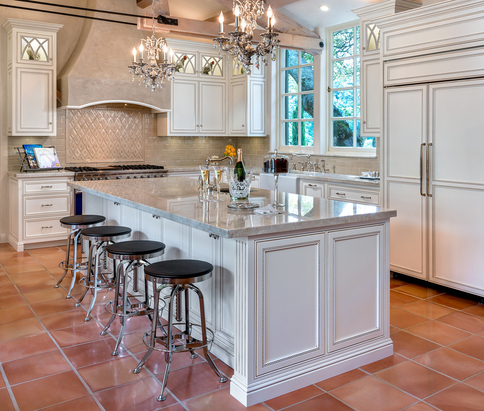 Eat-in kitchen - large traditional u-shaped terra-cotta tile eat-in kitchen idea in San Francisco with a farmhouse sink, glass-front cabinets, white cabinets, granite countertops, beige backsplash, subway tile backsplash, colored appliances and an island