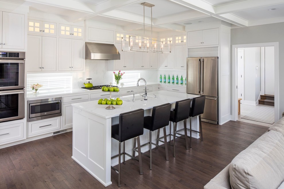 Inspiration for a classic galley open plan kitchen in Minneapolis with a single-bowl sink, shaker cabinets, white cabinets, white splashback, stainless steel appliances, dark hardwood flooring and an island.