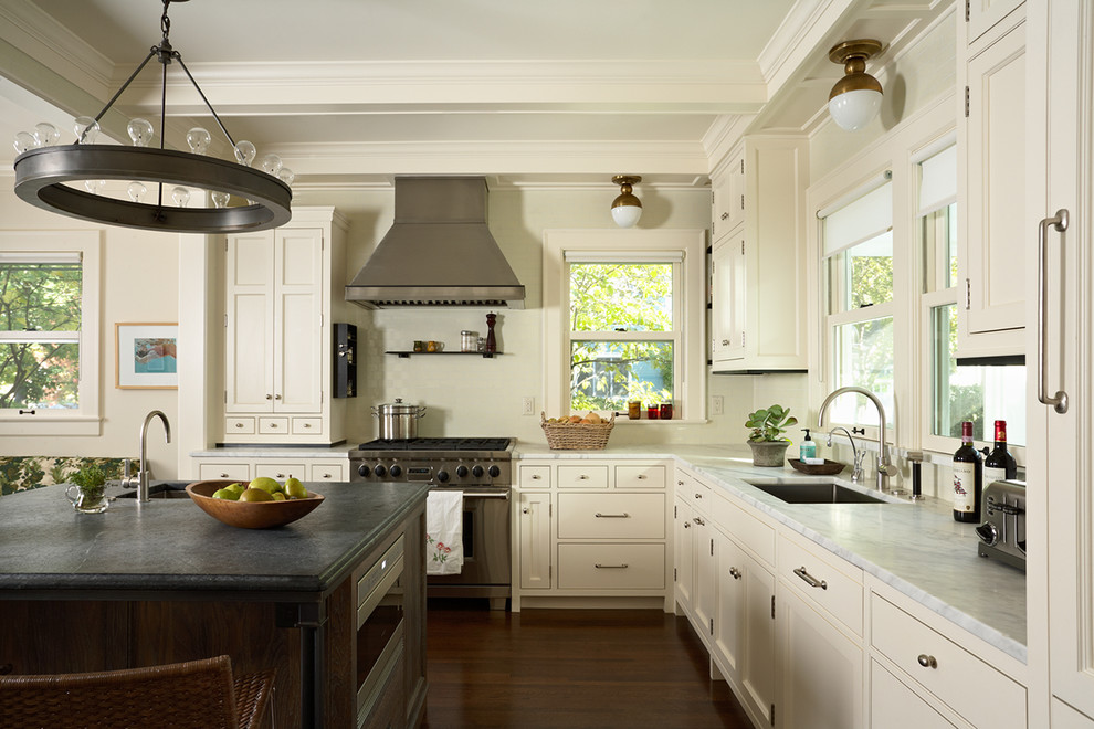 На фото: угловая кухня в классическом стиле с белыми фасадами и темным паркетным полом