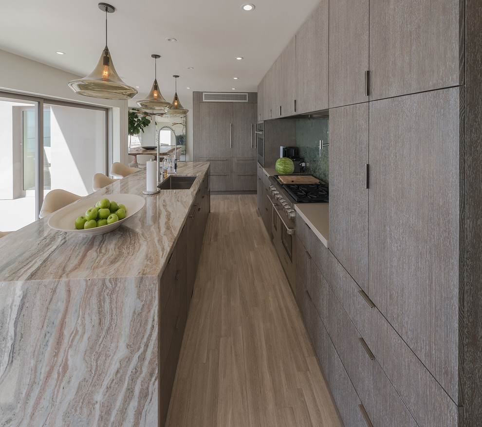 Mid-sized galley travertine floor eat-in kitchen photo in Los Angeles with an undermount sink, flat-panel cabinets, dark wood cabinets, marble countertops, black backsplash, mirror backsplash, paneled appliances and an island