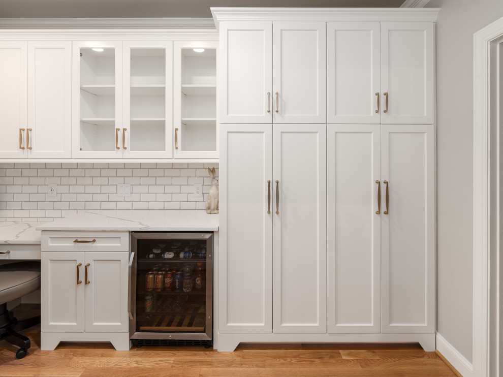 Idéer för stora vintage vitt kök, med en undermonterad diskho, luckor med infälld panel, vita skåp, bänkskiva i kvarts, vitt stänkskydd, stänkskydd i keramik, rostfria vitvaror, mellanmörkt trägolv, en köksö och brunt golv